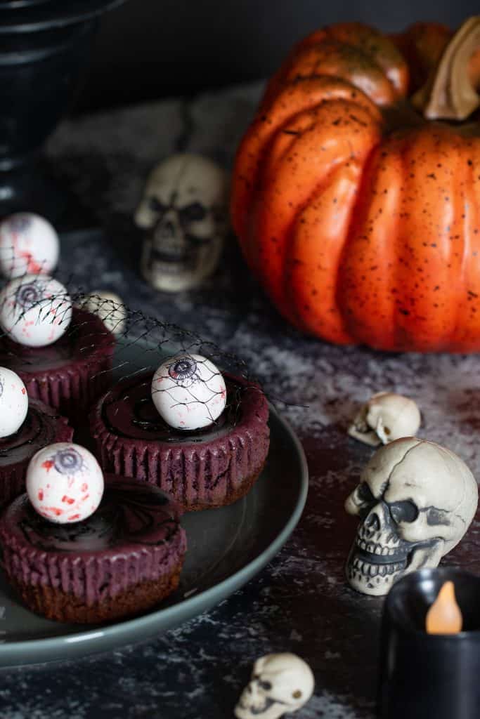 Table set with Halloween Graveyard Cheesecake Bites, a pumpkin, and skulls.