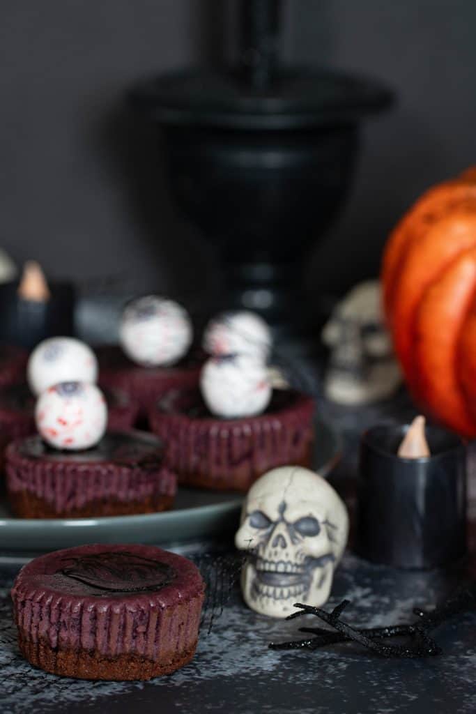 Skull in front of a plate of Halloween Graveyard Cheesecake Bites.