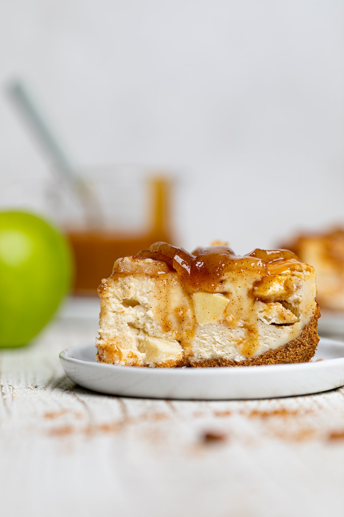 Slice of Caramel Apple Spice Cheesecake on a white plate.