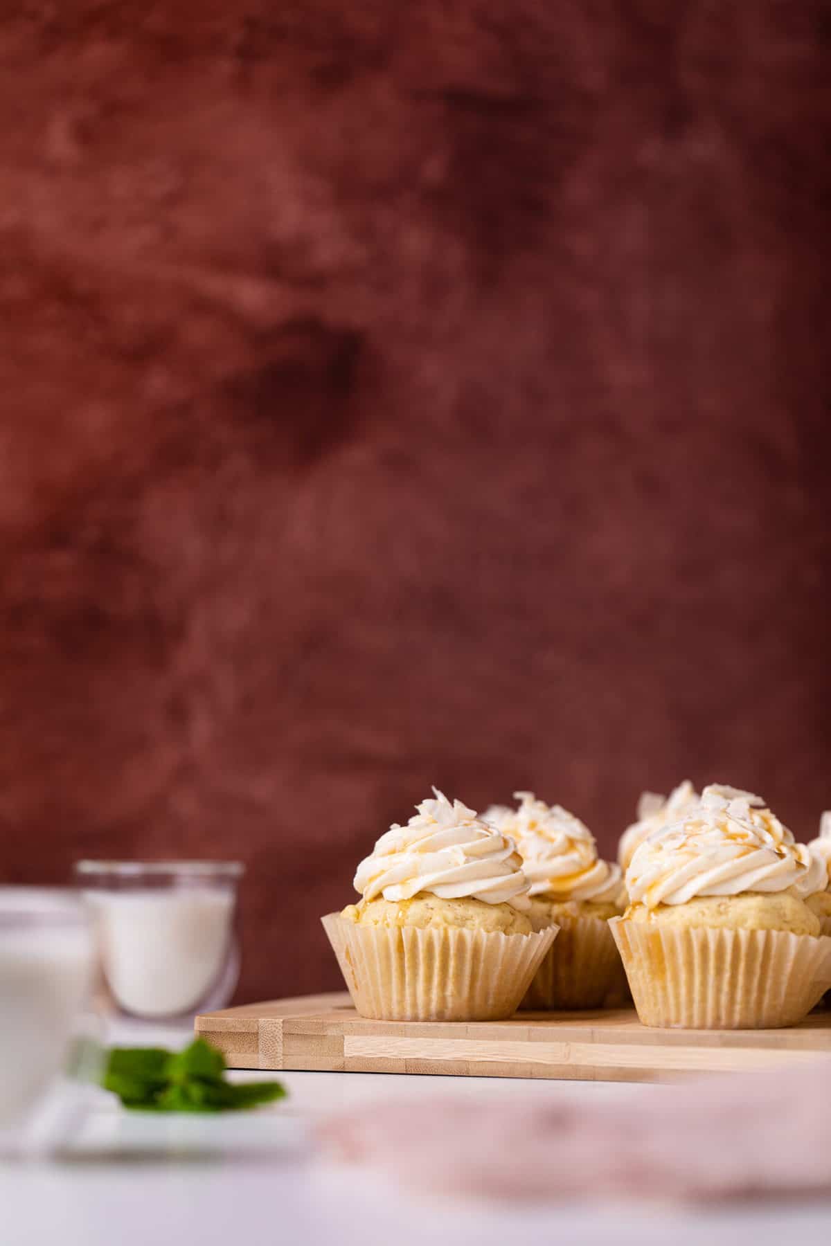 Easy Caramel Coconut Cupcakes in paper wrappers on a white surface on a cutting board.