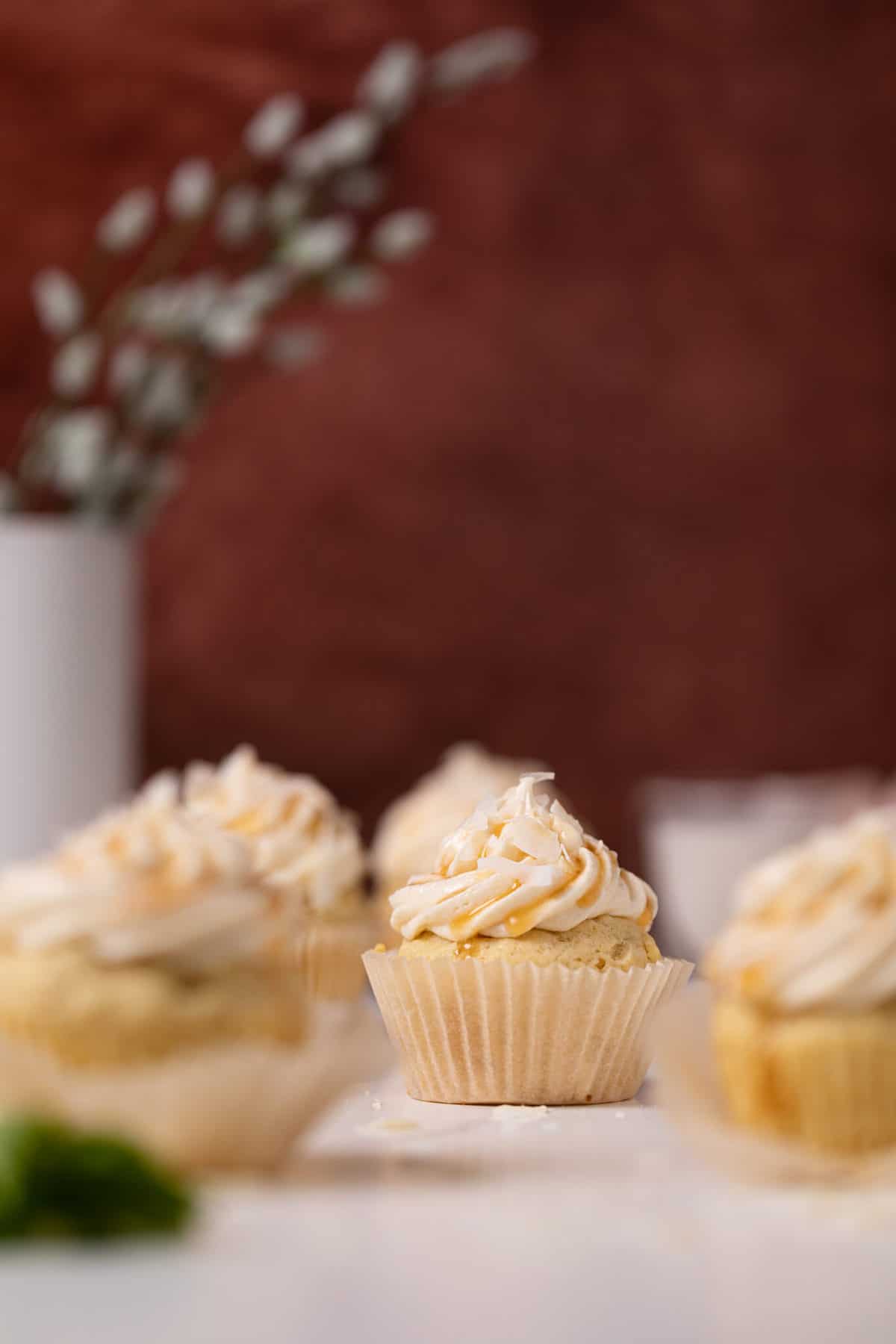 Easy Caramel Coconut Cupcakes in paper wrappers on a white surface