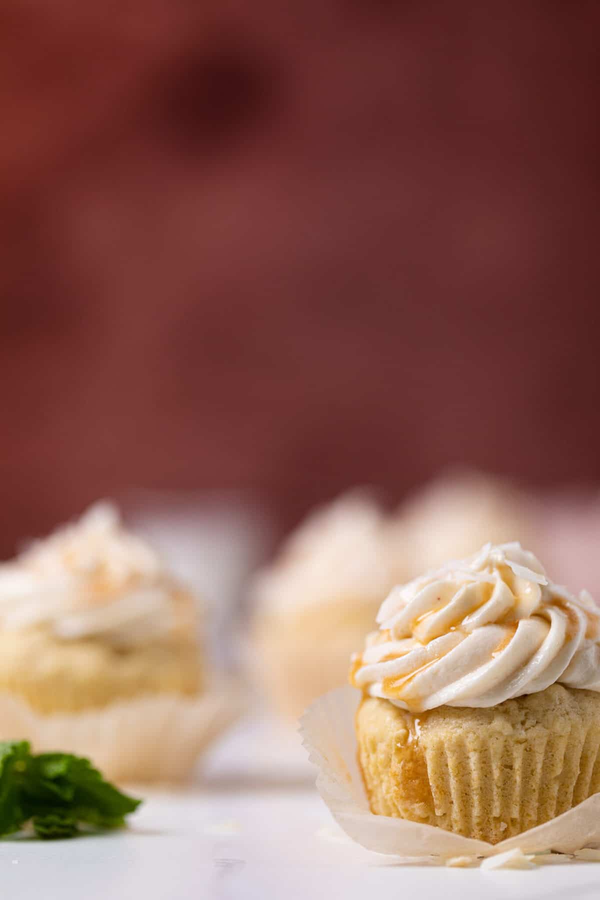 Easy Caramel Coconut Cupcakes in paper wrappers on a white surface
