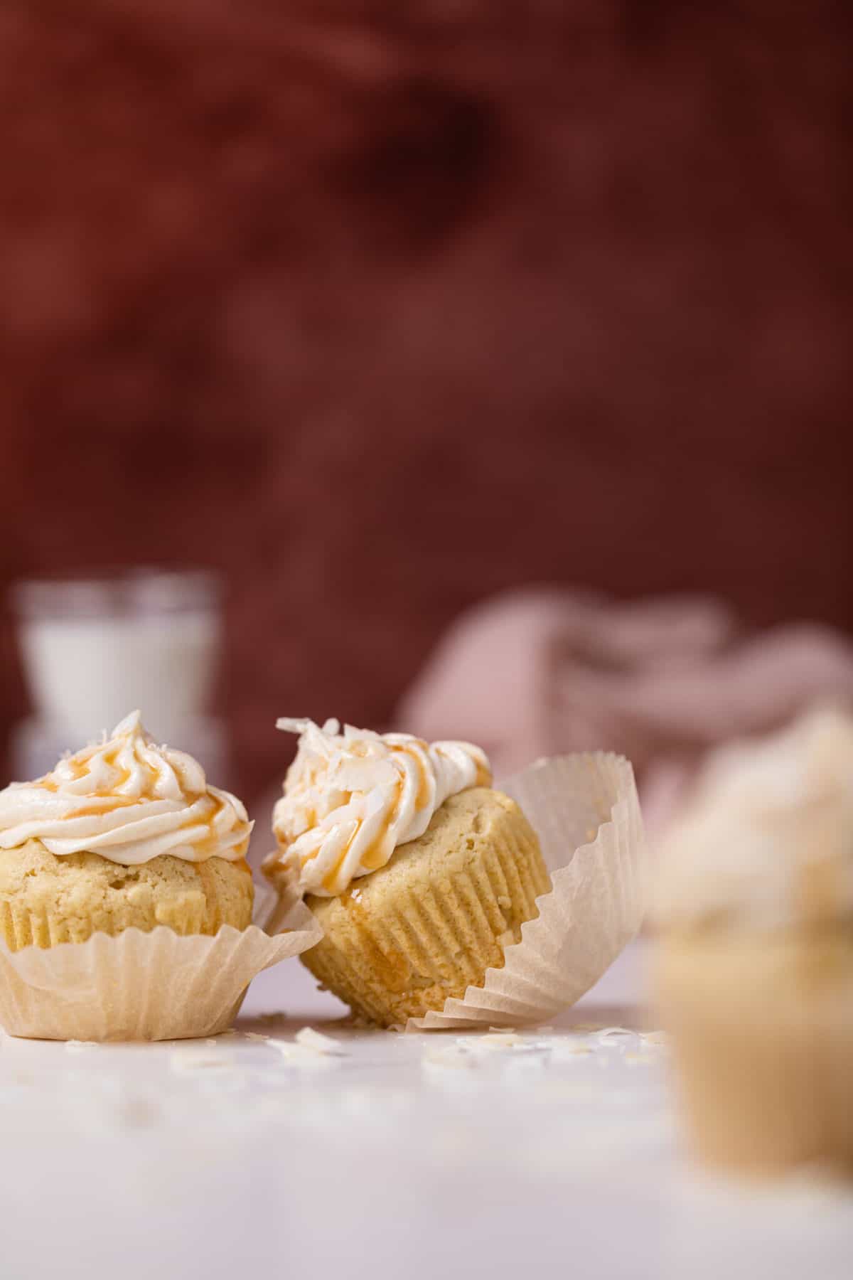 Easy Caramel Coconut Cupcakes in paper wrappers on a white surface