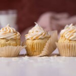 Easy Caramel Coconut Cupcakes in paper wrappers on a white surface.