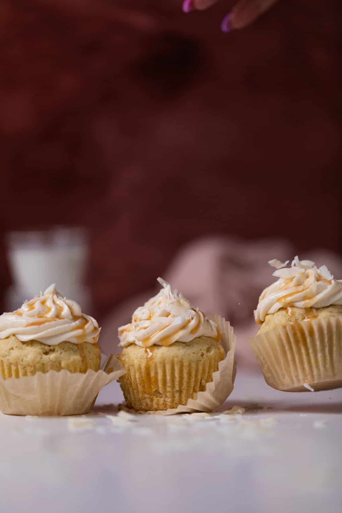 Easy Caramel Coconut Cupcakes in various positions on a table.