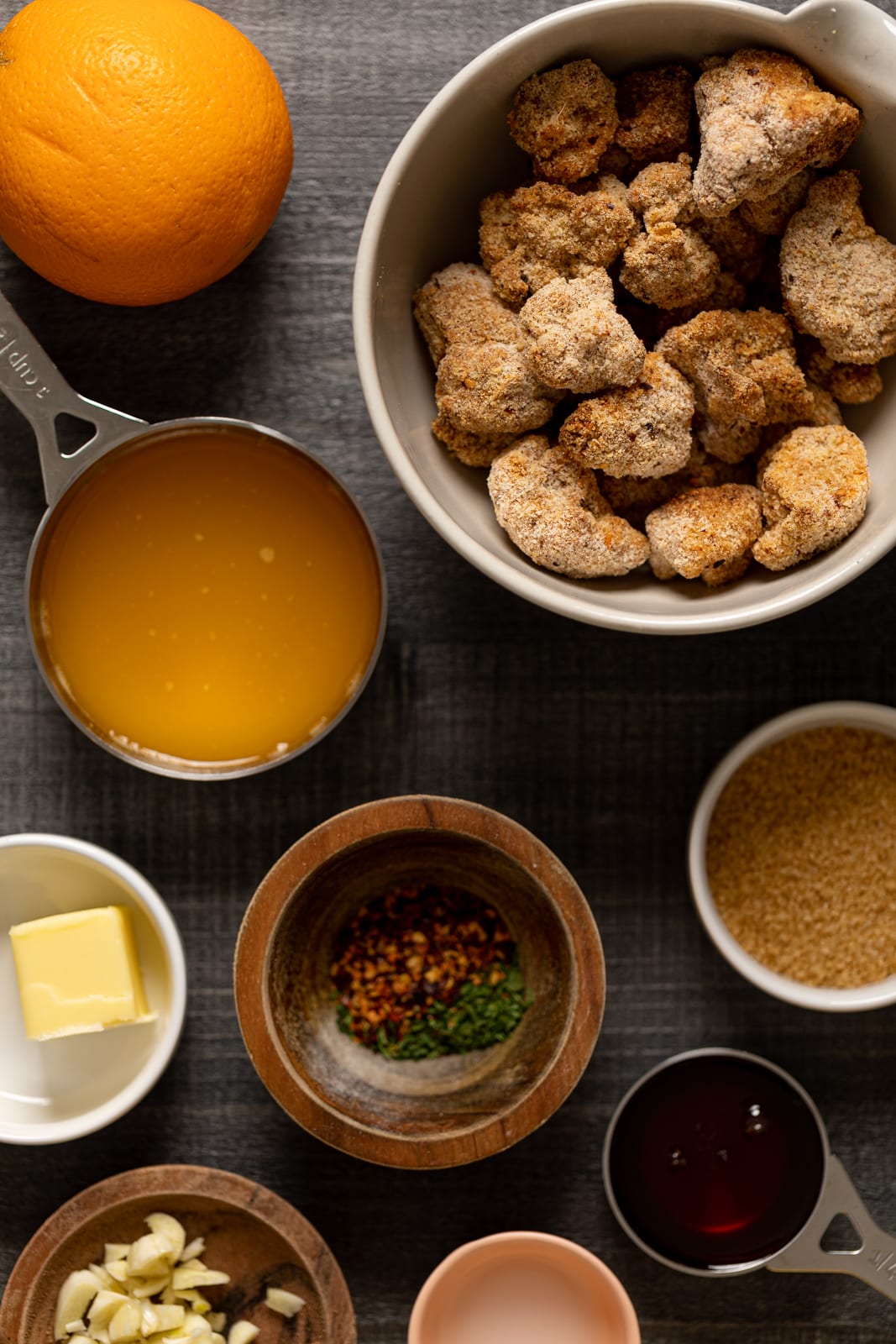 Ingredients for Baked Sticky Orange Cauliflower including butter, breaded cauliflower, and crushed red pepper