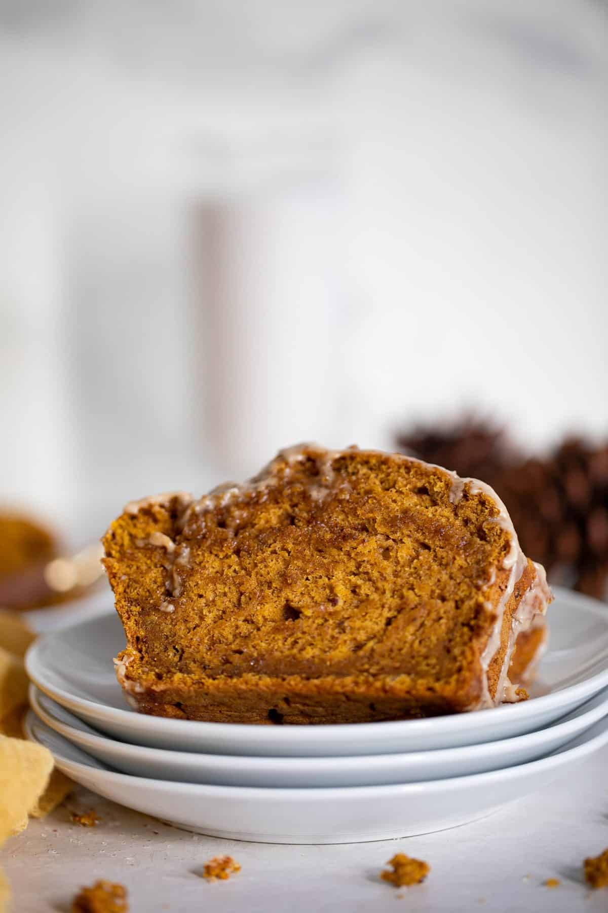 Slices of Vegan Pumpkin Bread with Maple Chai Frosting on small, stacked, white plates.