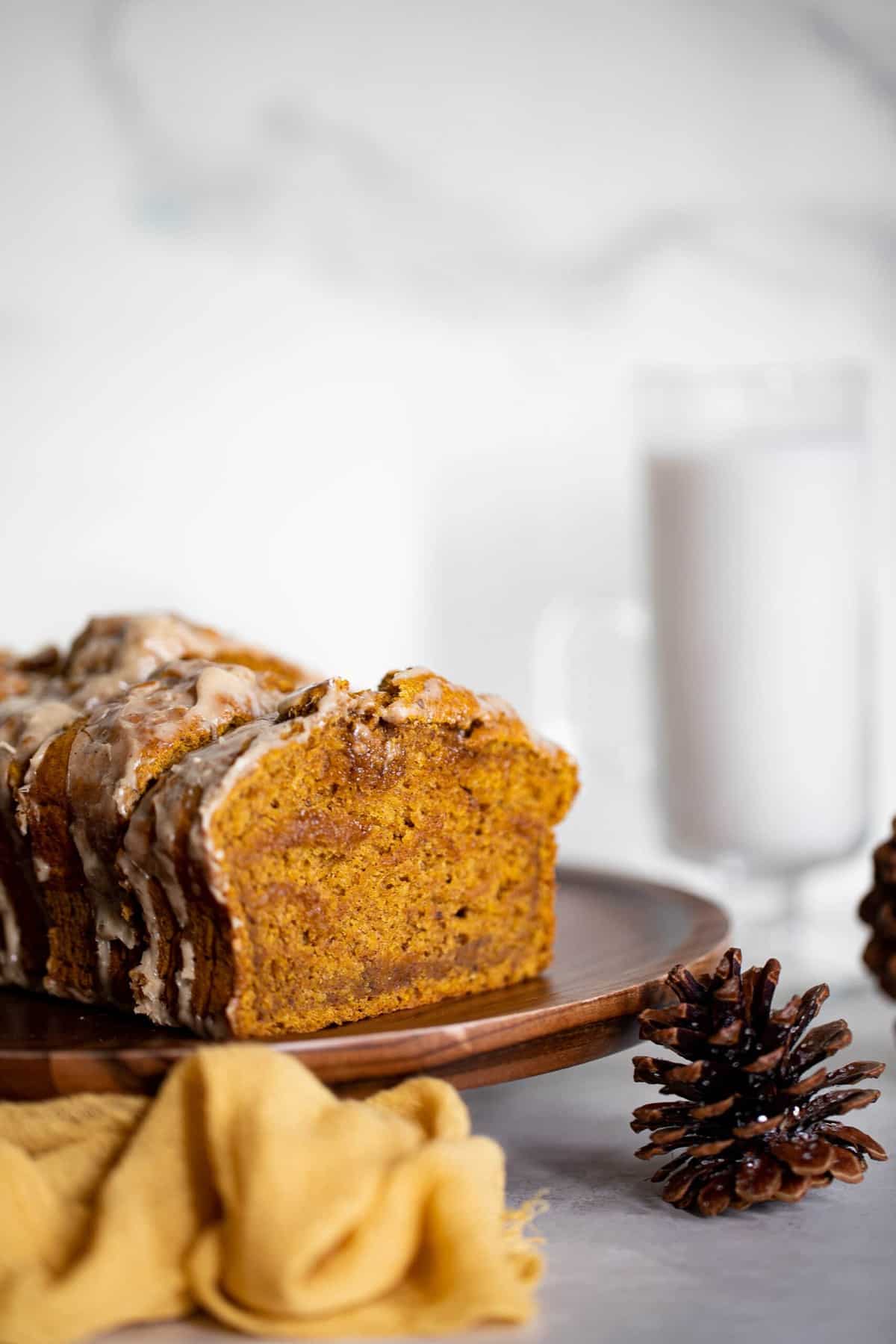 Slices of Vegan Pumpkin Bread with Maple Chai Frosting on a wooden board.