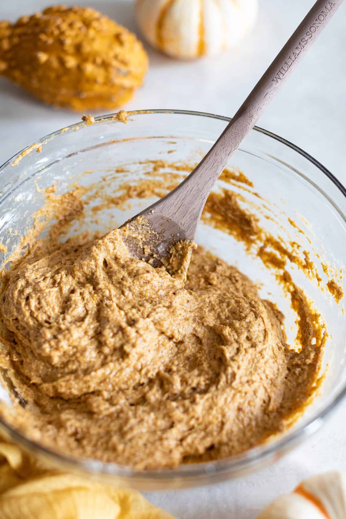 Spoon stirring Vegan Pumpkin Bread dough in a glass bowl.