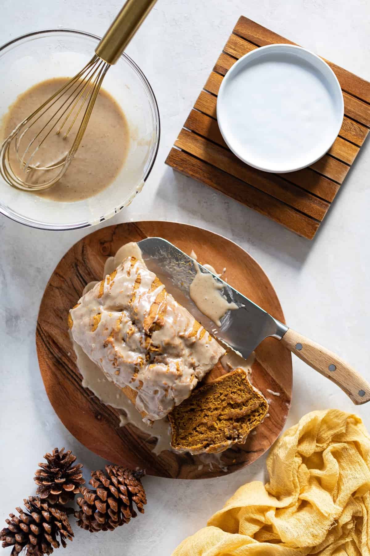 Vegan Pumpkin Bread with Maple Chai Frosting on a wooden board with a knife.