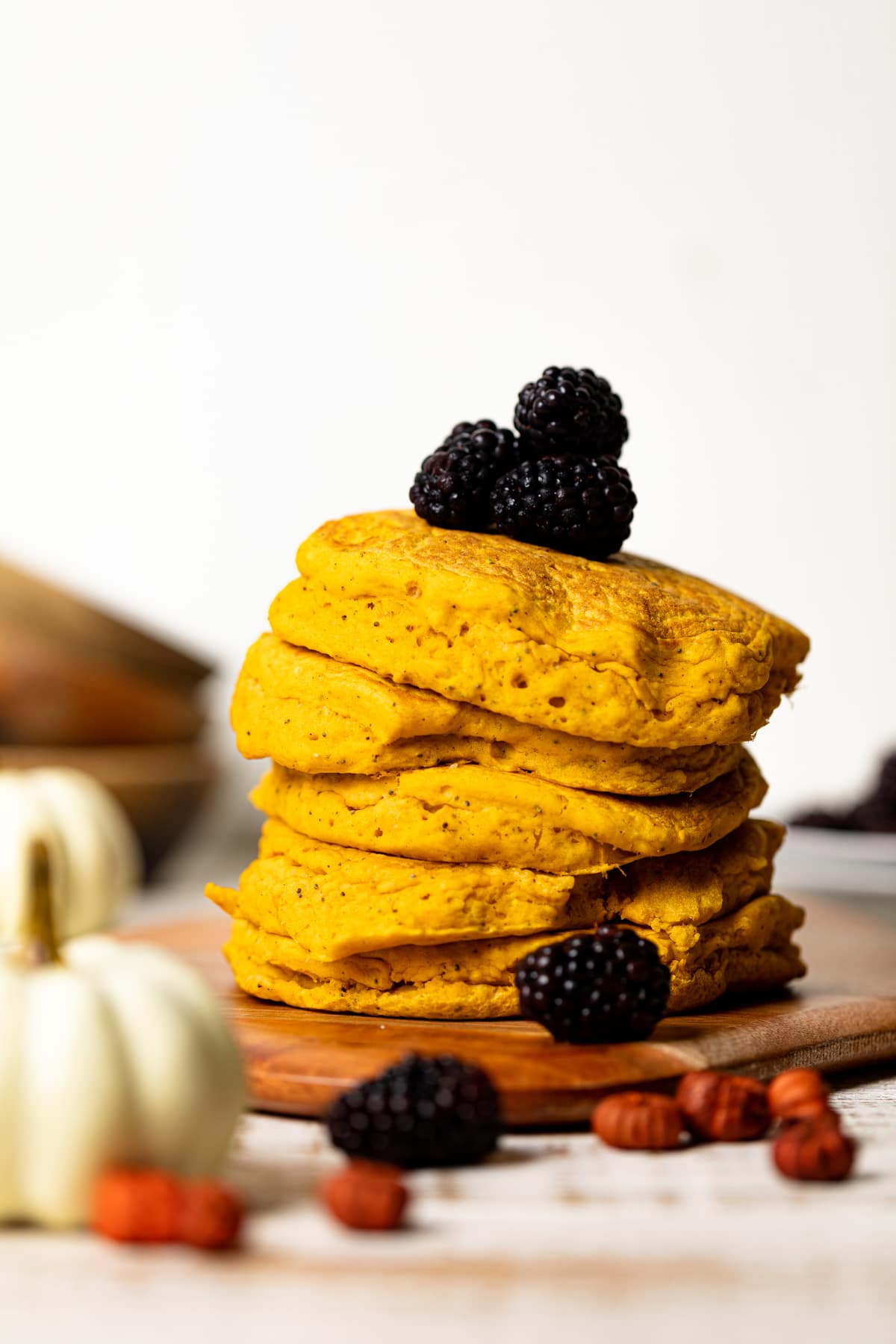 Stack of Vegan Pumpkin Poppyseed Pancakes topped with blackberries and on a wooden board