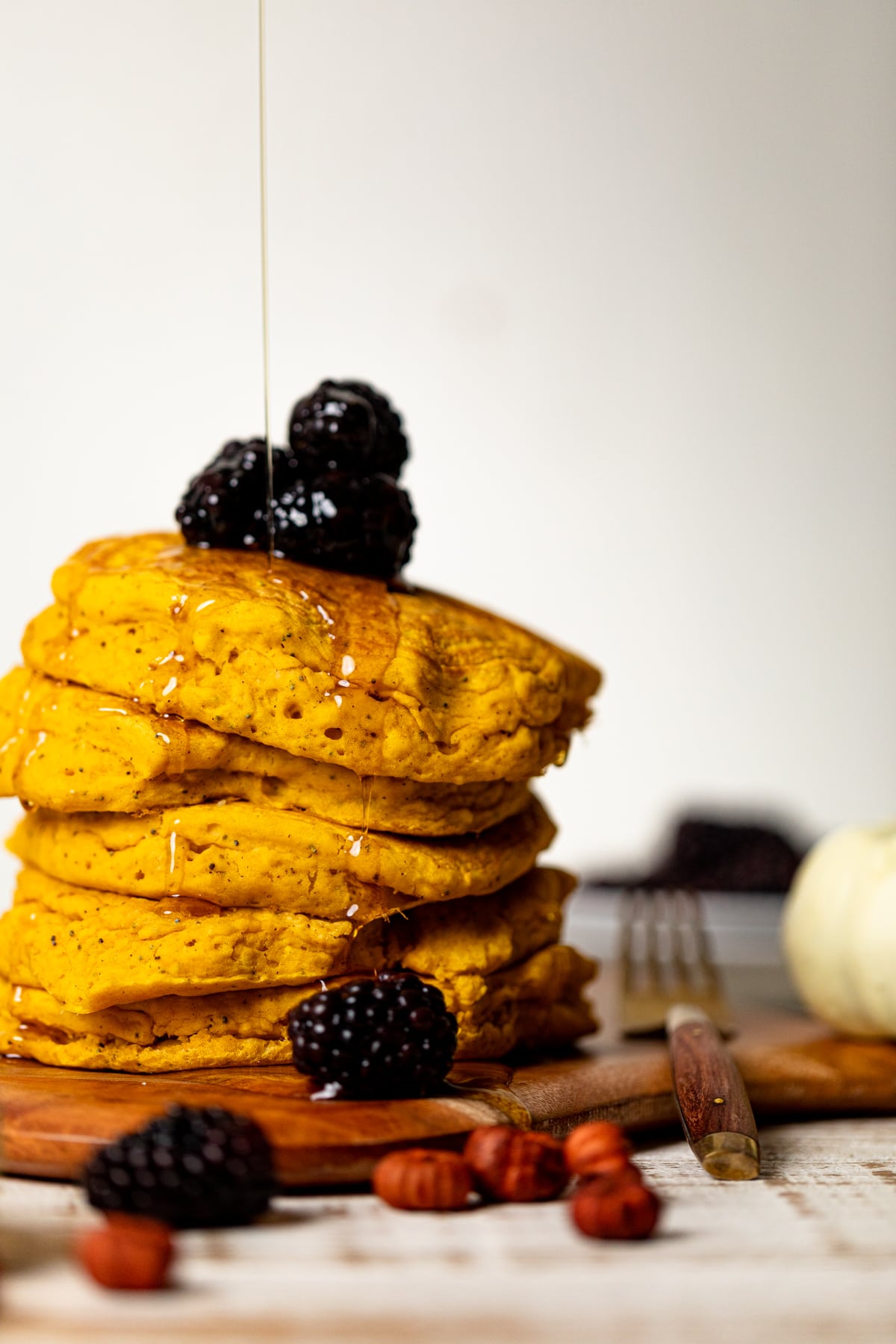 Syrup drizzling onto a stack of Vegan Pumpkin Poppyseed Pancakes