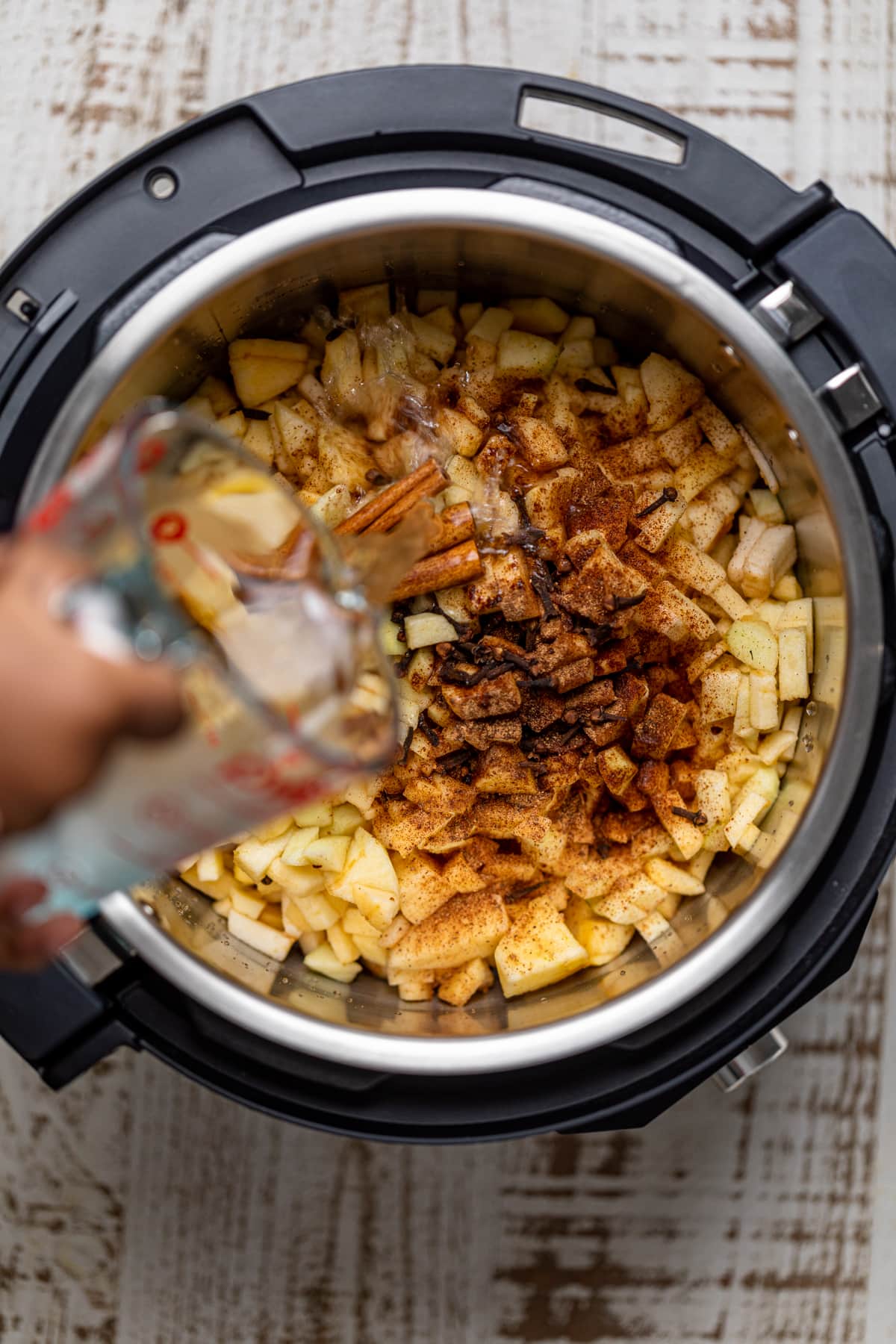 Woman pouring water into a slow cooker.