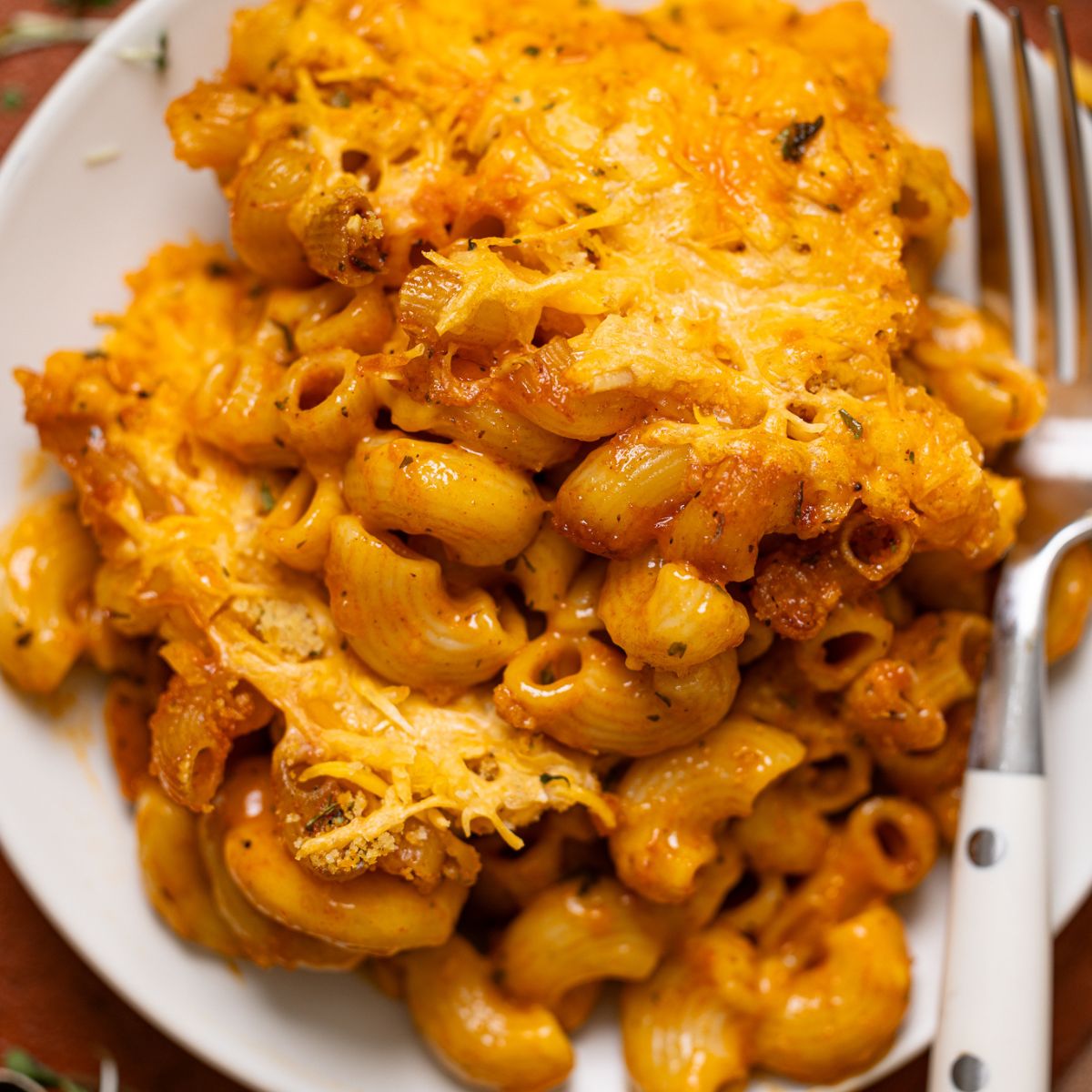 Up close shot of Baked Vegan Buffalo Mac + Cheese on a plate with a fork.