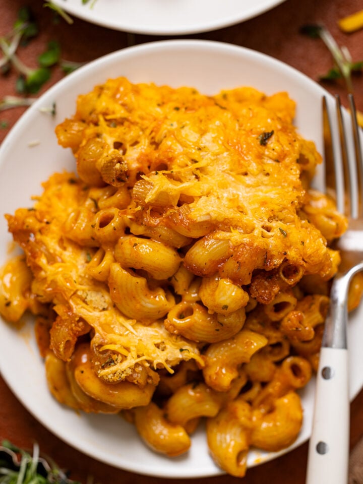 Up close shot of Baked Vegan Buffalo Mac + Cheese on a plate with a fork.