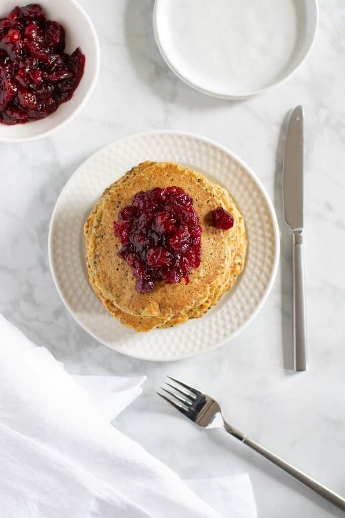Stack of Vegan Quinoa Pancakes topped with Cranberries on a plate.