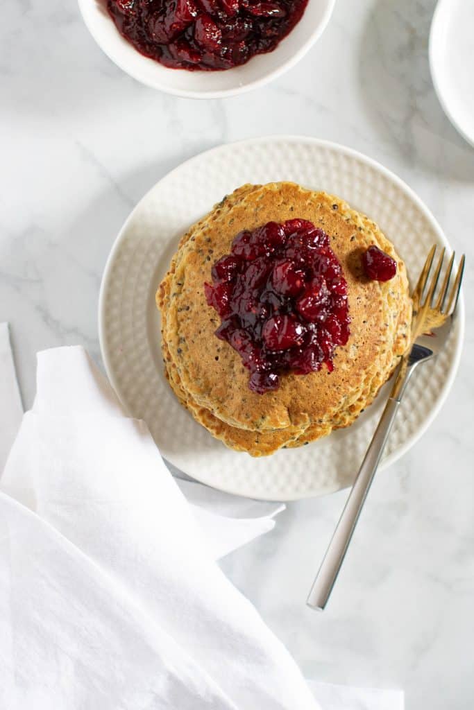 Plate of Vegan Quinoa Pancakes topped with Cranberries and a fork.