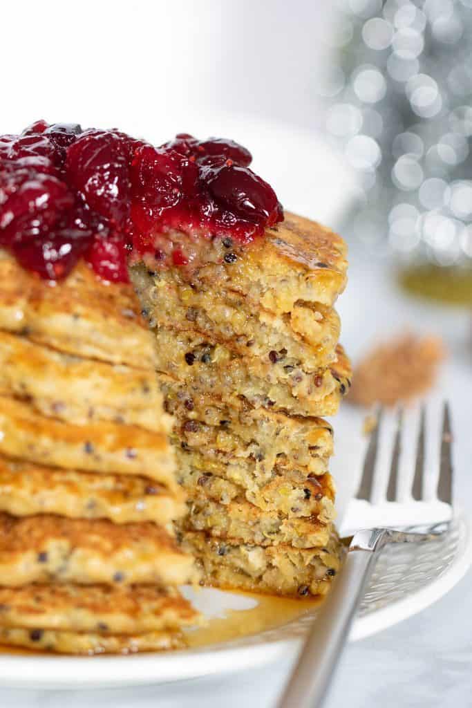 Stack of Vegan Quinoa Pancakes topped with Cranberries missing a slice.