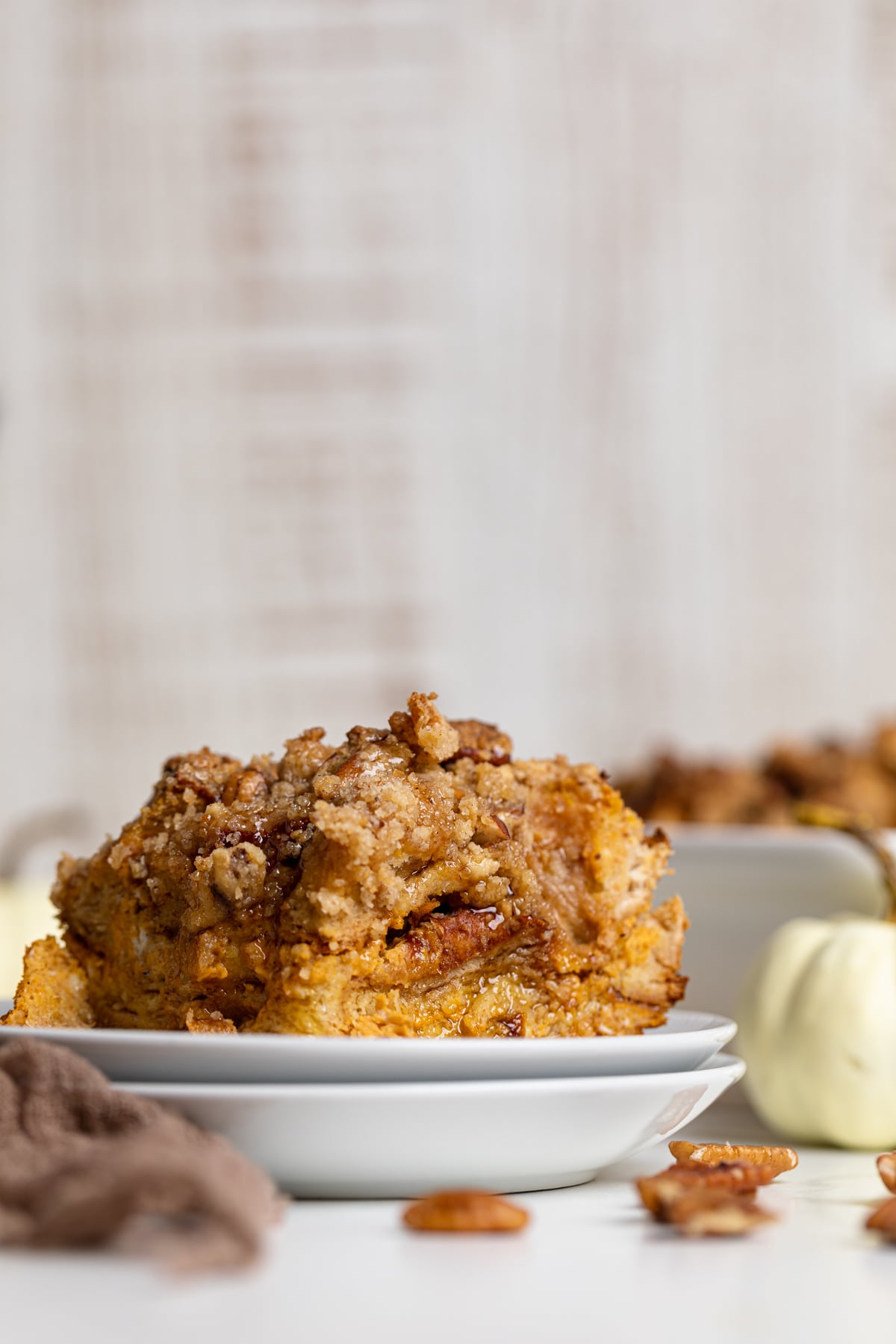 Piece of Baked Pumpkin French Toast Casserole on two small, stacked plates on a white table