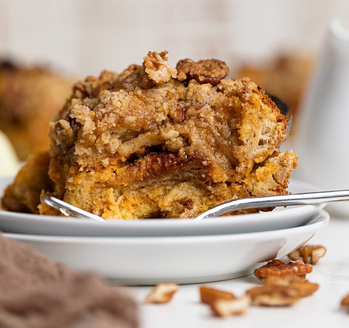 Piece of Baked Pumpkin French Toast Casserole and a fork on two small, stacked plates