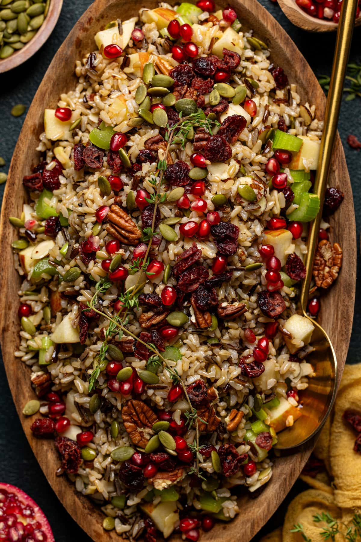 Up close shot of wild rice in a serving bowl with a gold serving spoon.