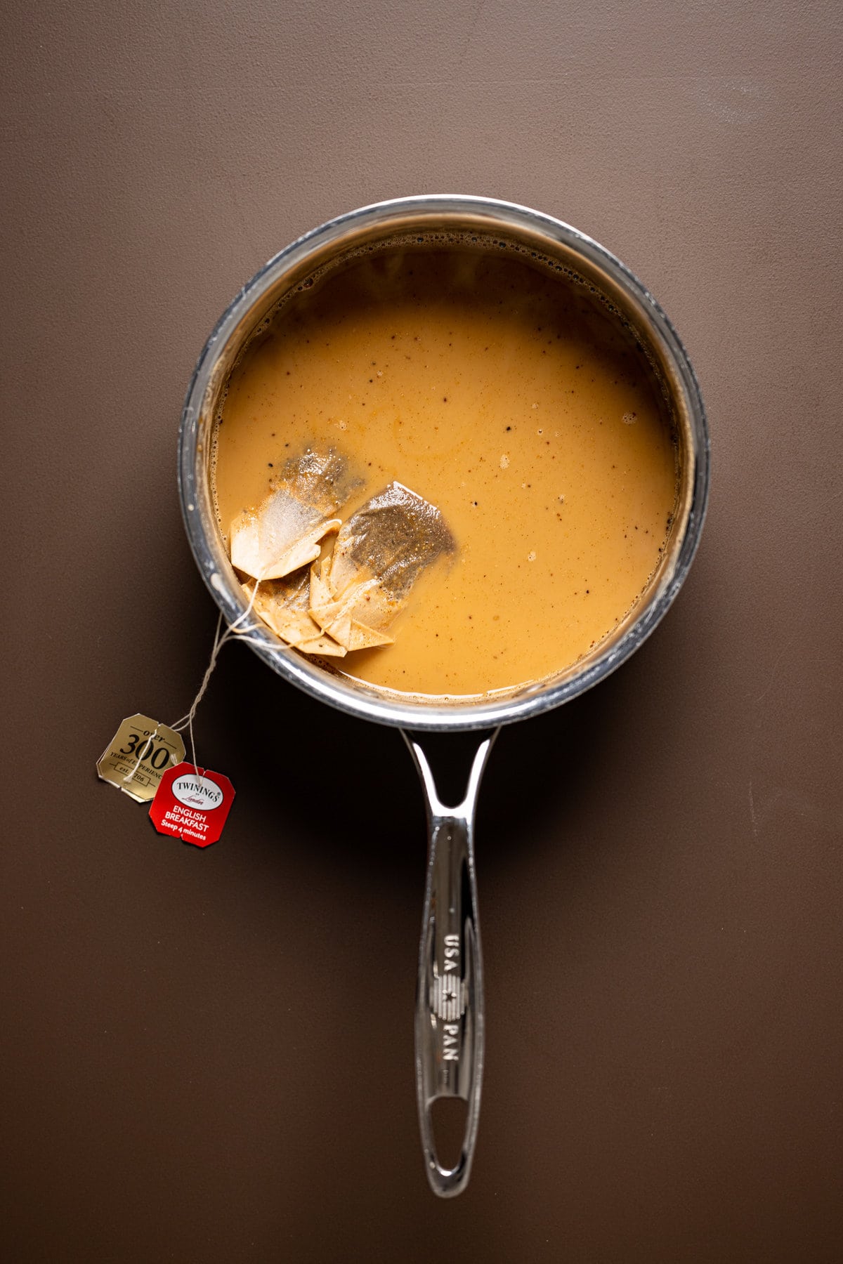 Teabags floating in a saucepan of chai tea