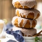 Vegan Gingerbread Donuts with Chai Glaze stacked on white plates.