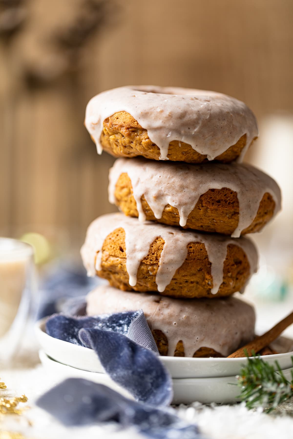 Vegan Gingerbread Donuts with Chai Glaze stacked on white plates.