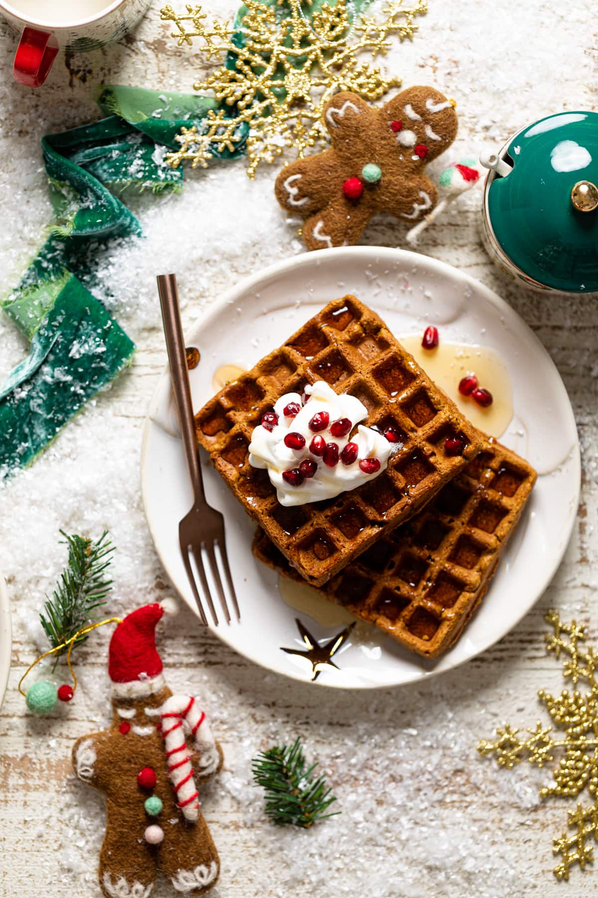 Gluten-free Flourless Gingerbread Waffles on a plate with a fork surrounded by Christmas decorations.