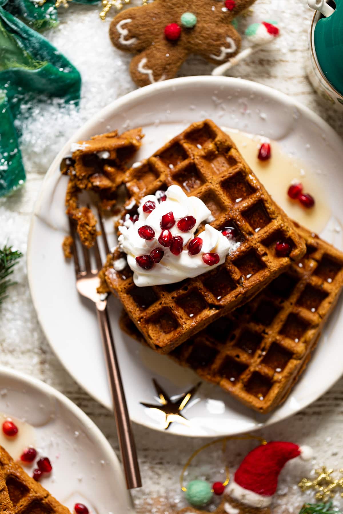 Gluten-free Flourless Gingerbread Waffles topped with whipped cream and pomegranate arils.