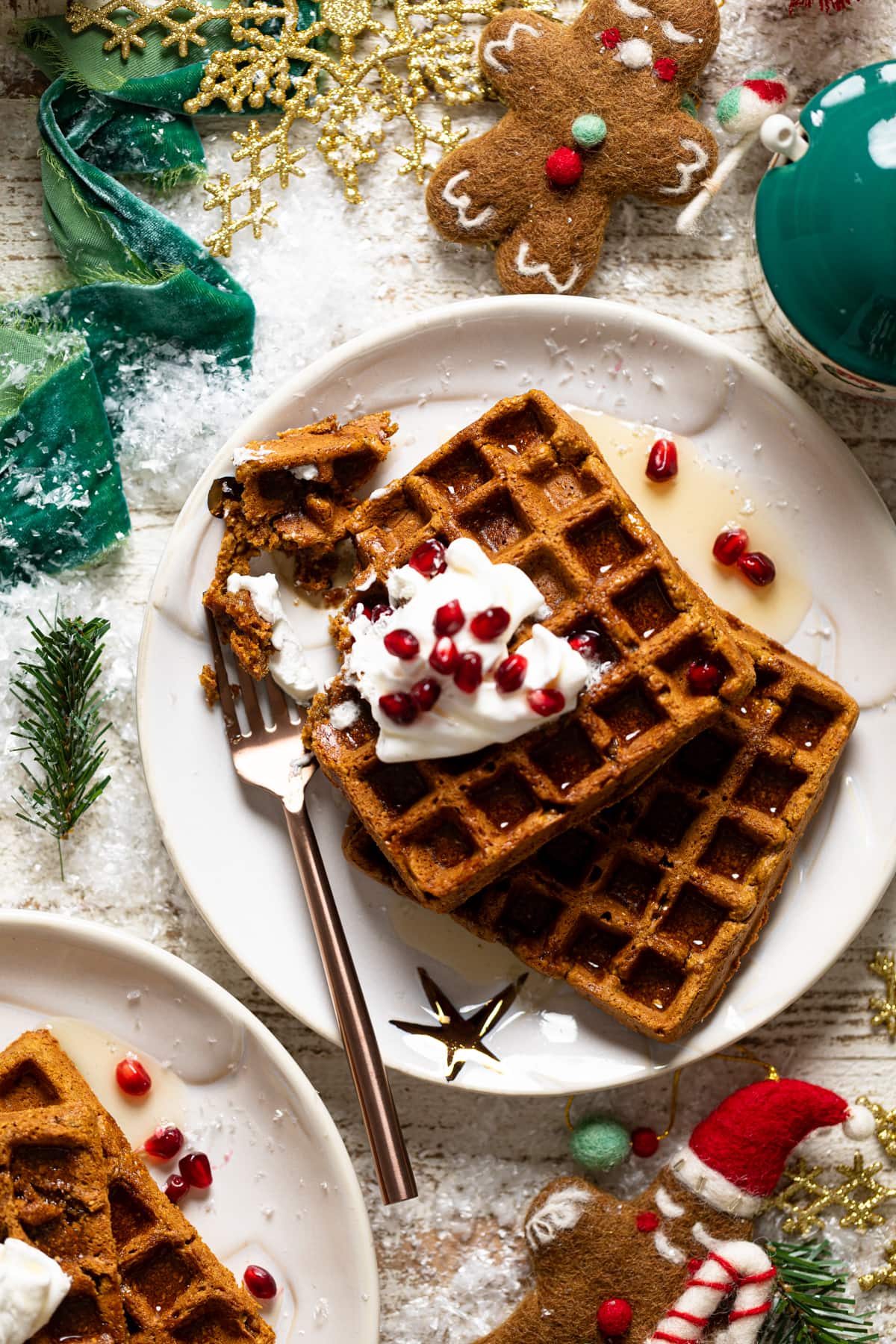 Gluten-free Flourless Gingerbread Waffles on a plate with a fork surrounded by Christmas decorations.