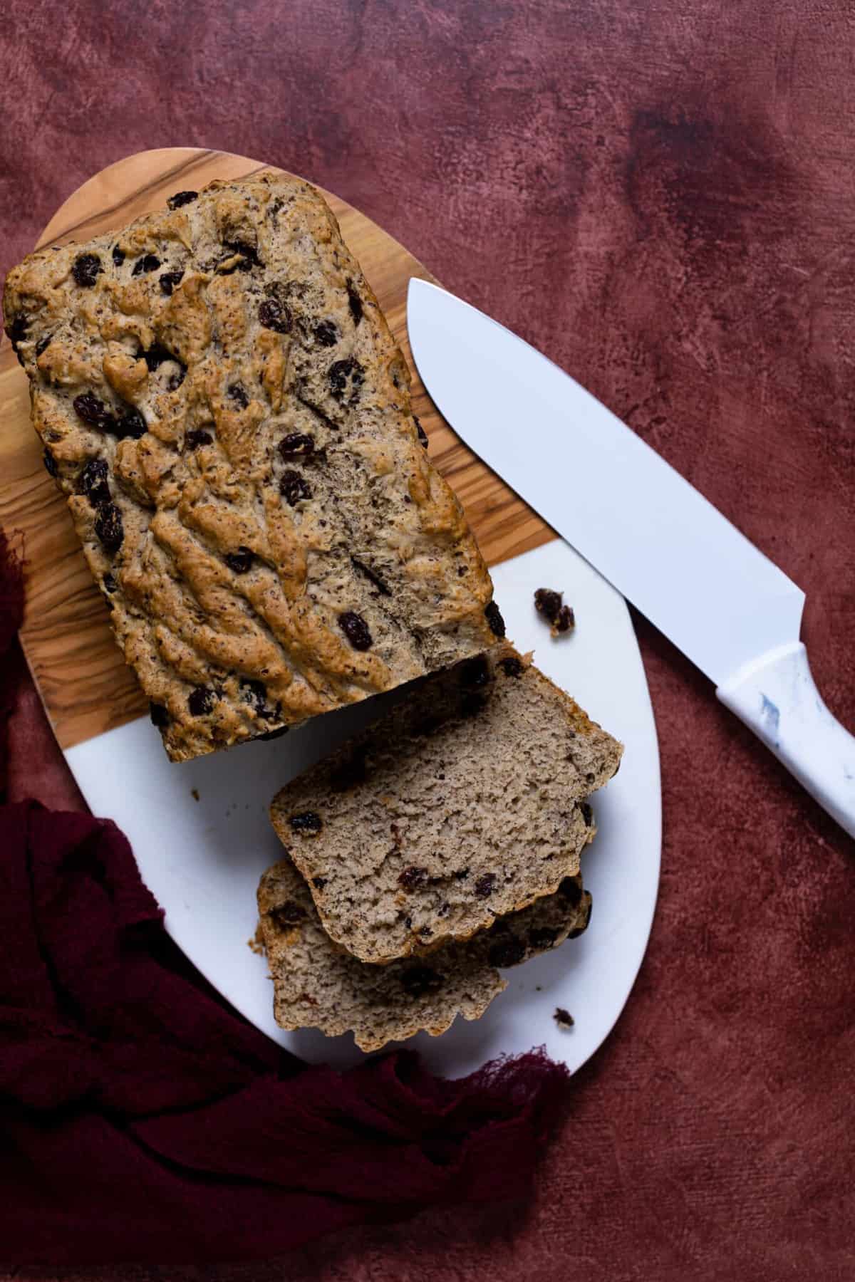 Homemade Rum Raisin Bread on a cutting board with a white knife.