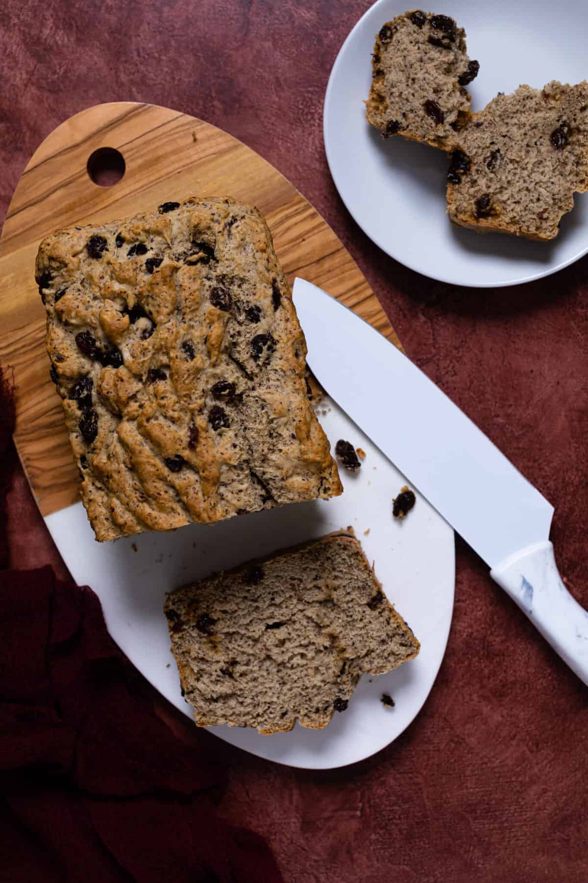 Homemade Rum and Raisin Bread on a wooden cutting board with a slice cut away.