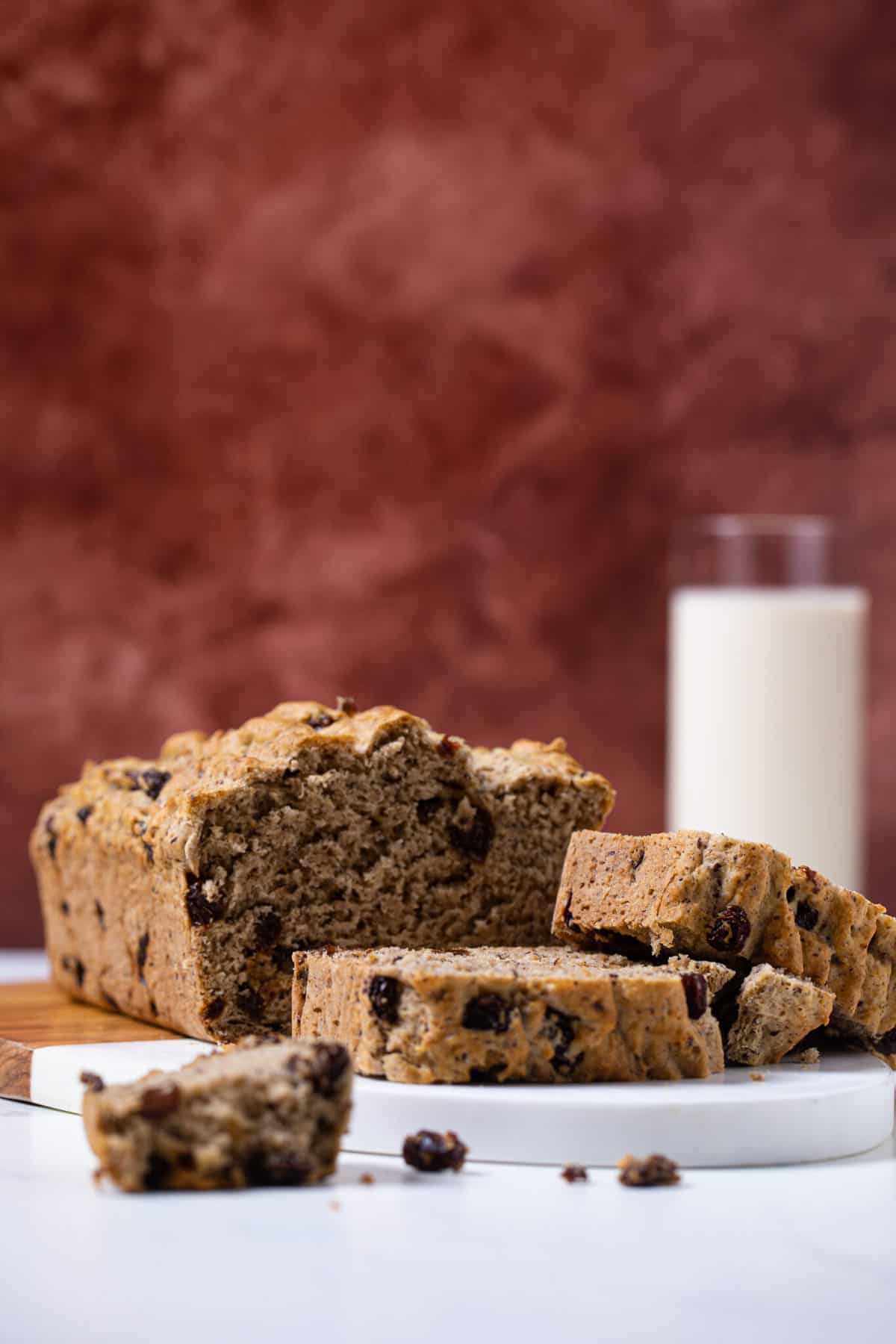 Homemade Rum and Raisin Bread on a cutting board with slices stacked on top of each other.