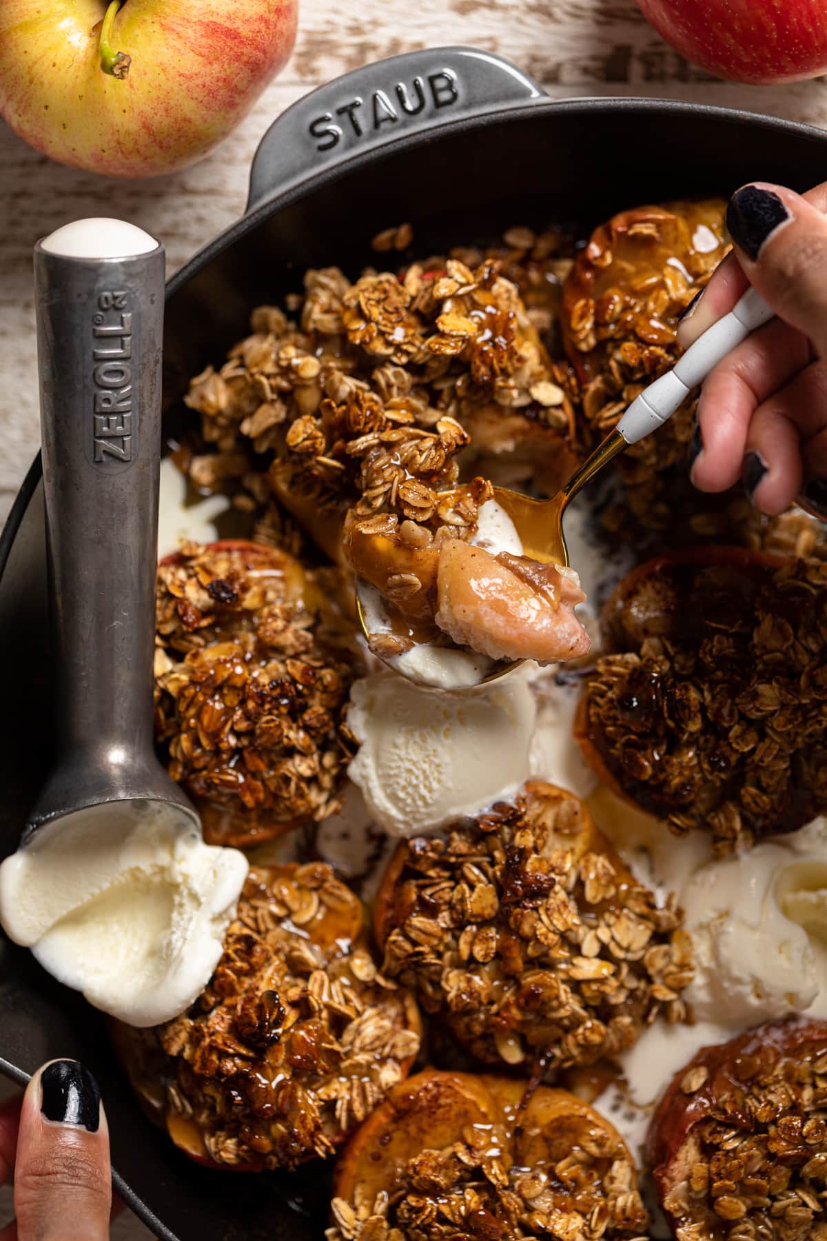 Spoon scooping Vegan Baked Cinnamon Caramel Apples and dairy-free ice cream.