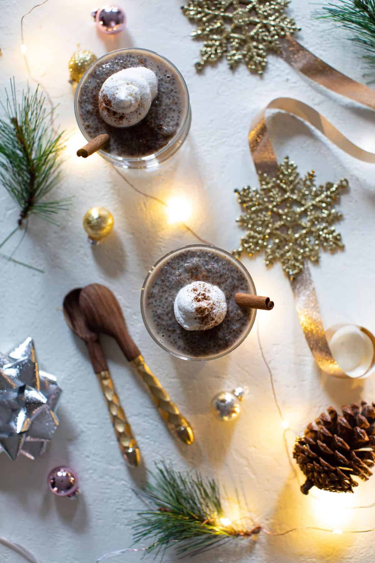 Table set with glasses of Chai Latte Chia Pudding, utensils, and Christmas decorations.