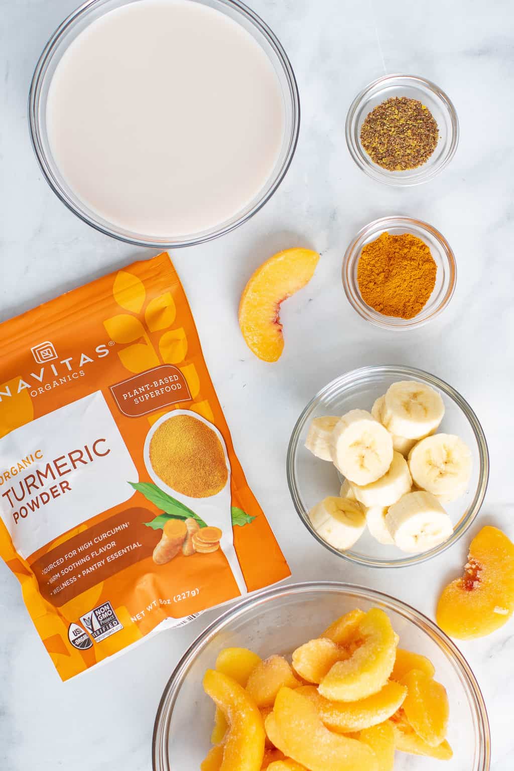 Ingredients including Navitas organic turmeric powder, sliced bananas, and frozen peaches.