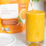 Glass of Turmeric 'Wake Up' Smoothie in front of a bag of Navitas turmeric powder