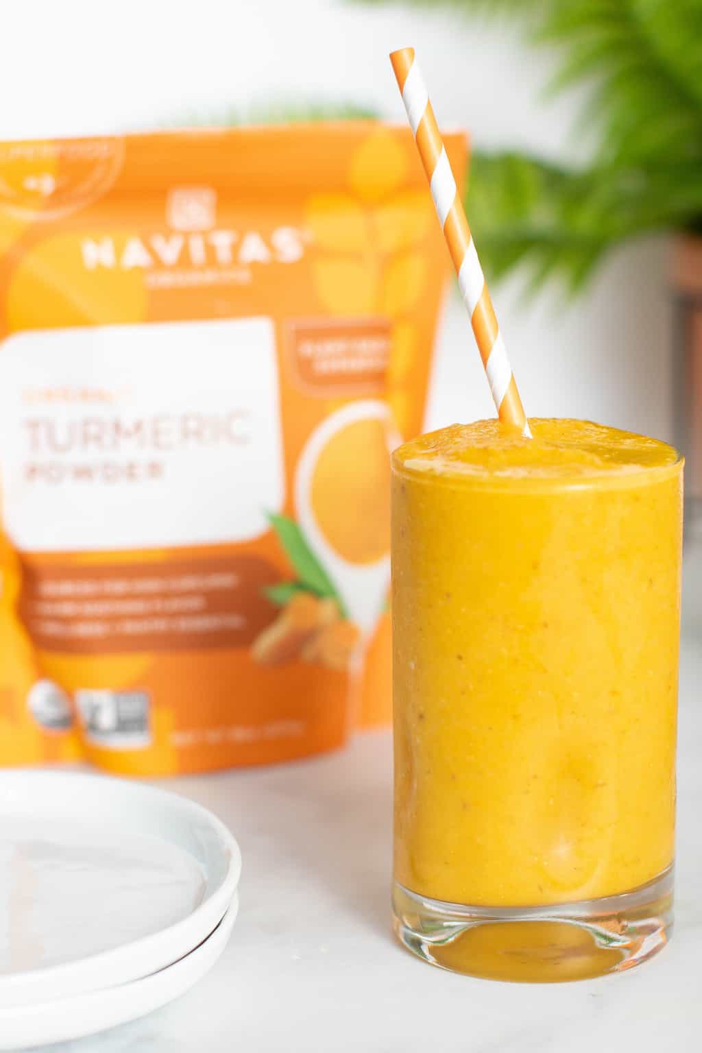 Glass of Turmeric \'Wake Up\' Smoothie in front of a bag of Navitas turmeric powder