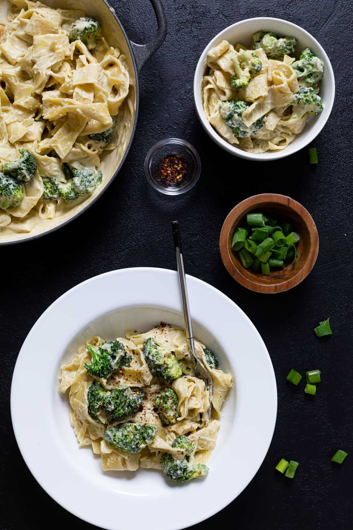 Plate, bowl, and pan of Vegan Broccoli Alfredo Pasta.