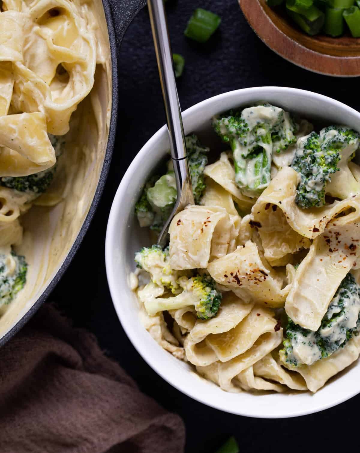 Fork in a white bowl of Vegan Broccoli Alfredo Pasta.