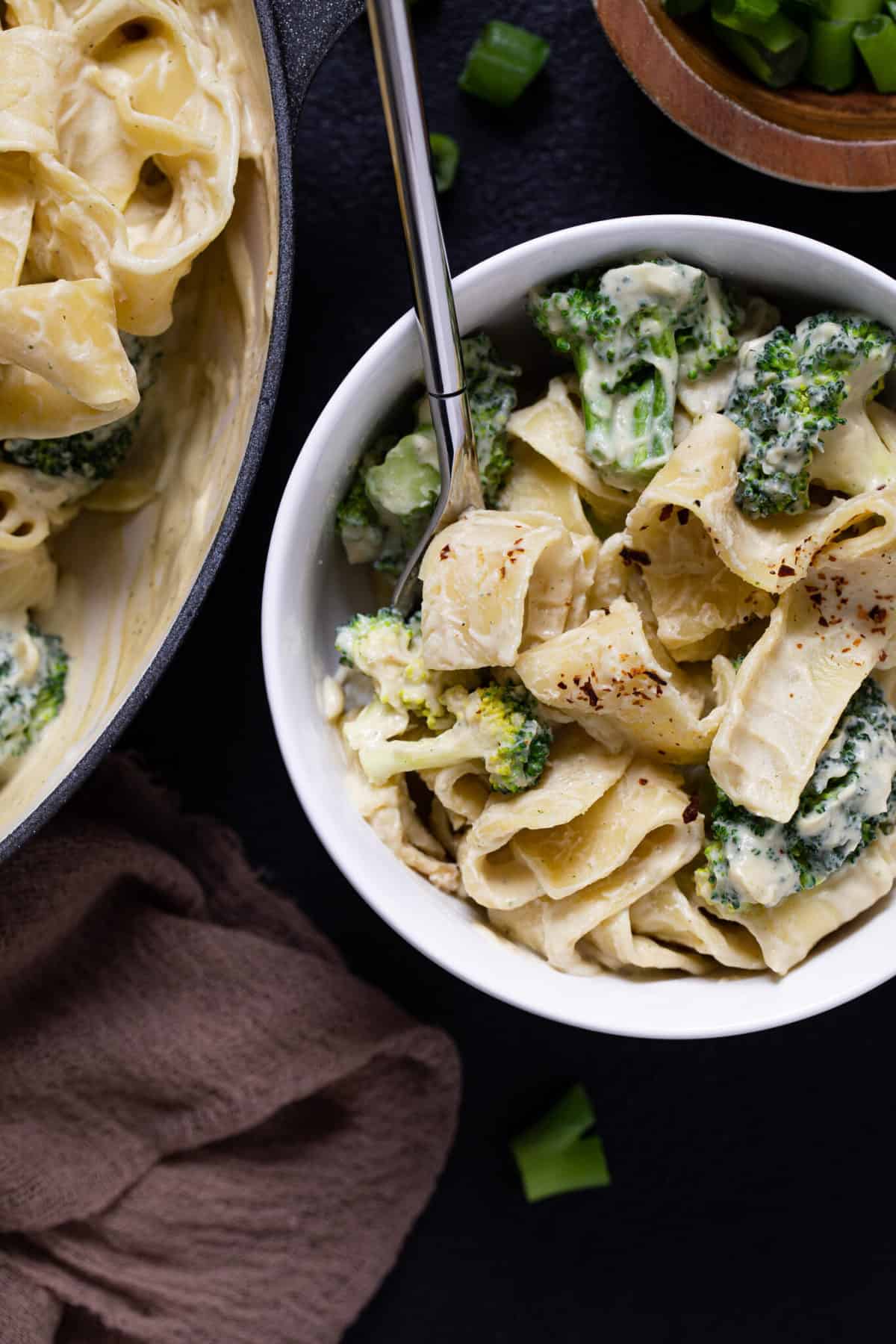 Fork in a white bowl of Vegan Broccoli Alfredo Pasta.