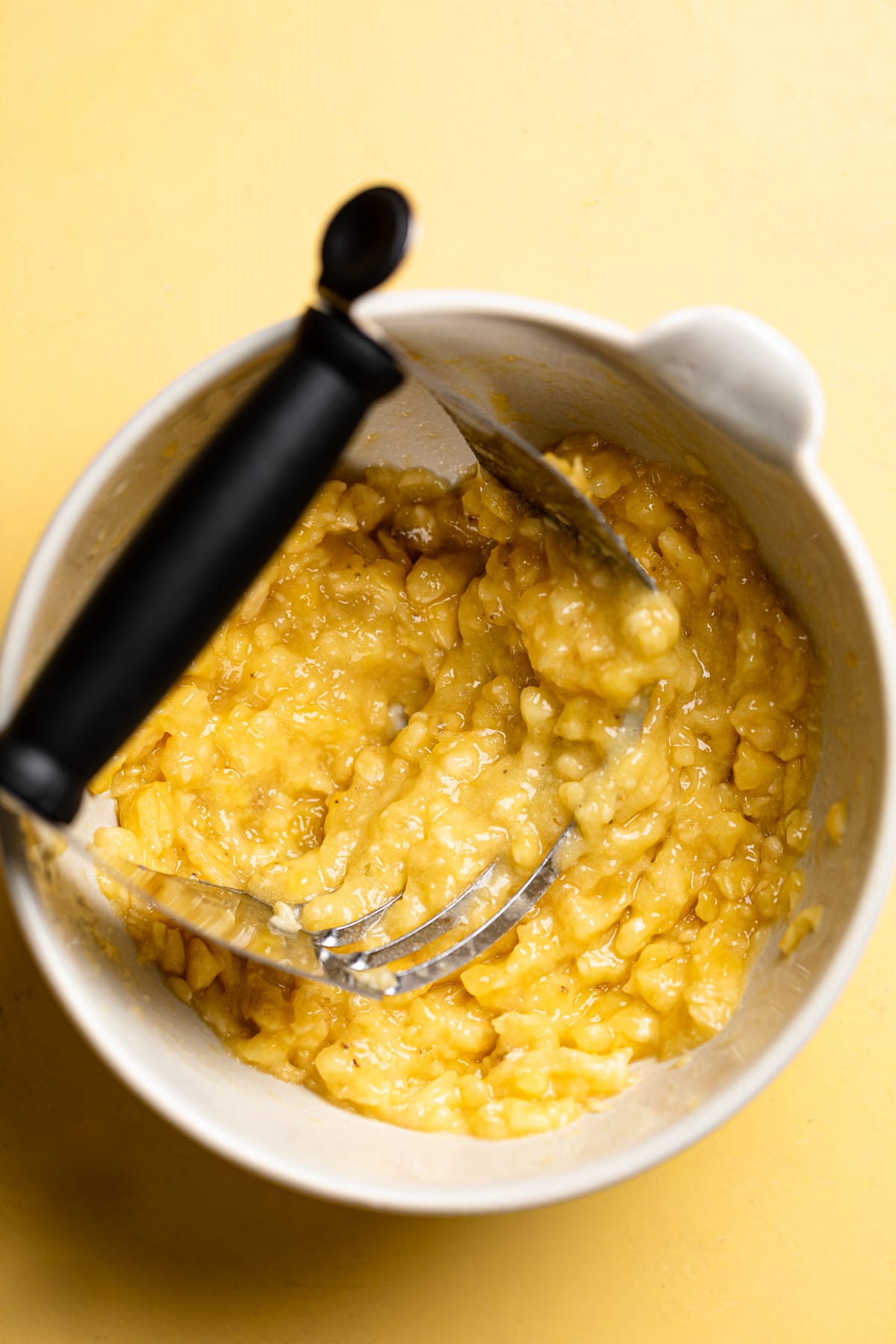 Pastry blender in a bowl of mashed bananas