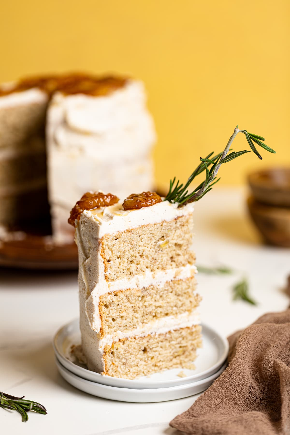 Slice of Vegan Banana Cake with Maple Buttercream on two small, stacked plates