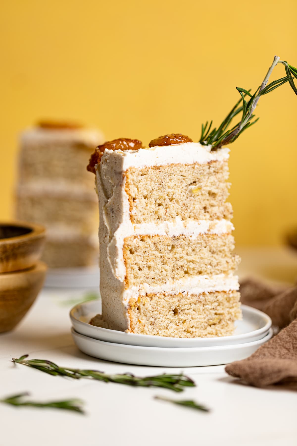 Slice of Vegan Banana Cake with Maple Buttercream on two small, stacked plates