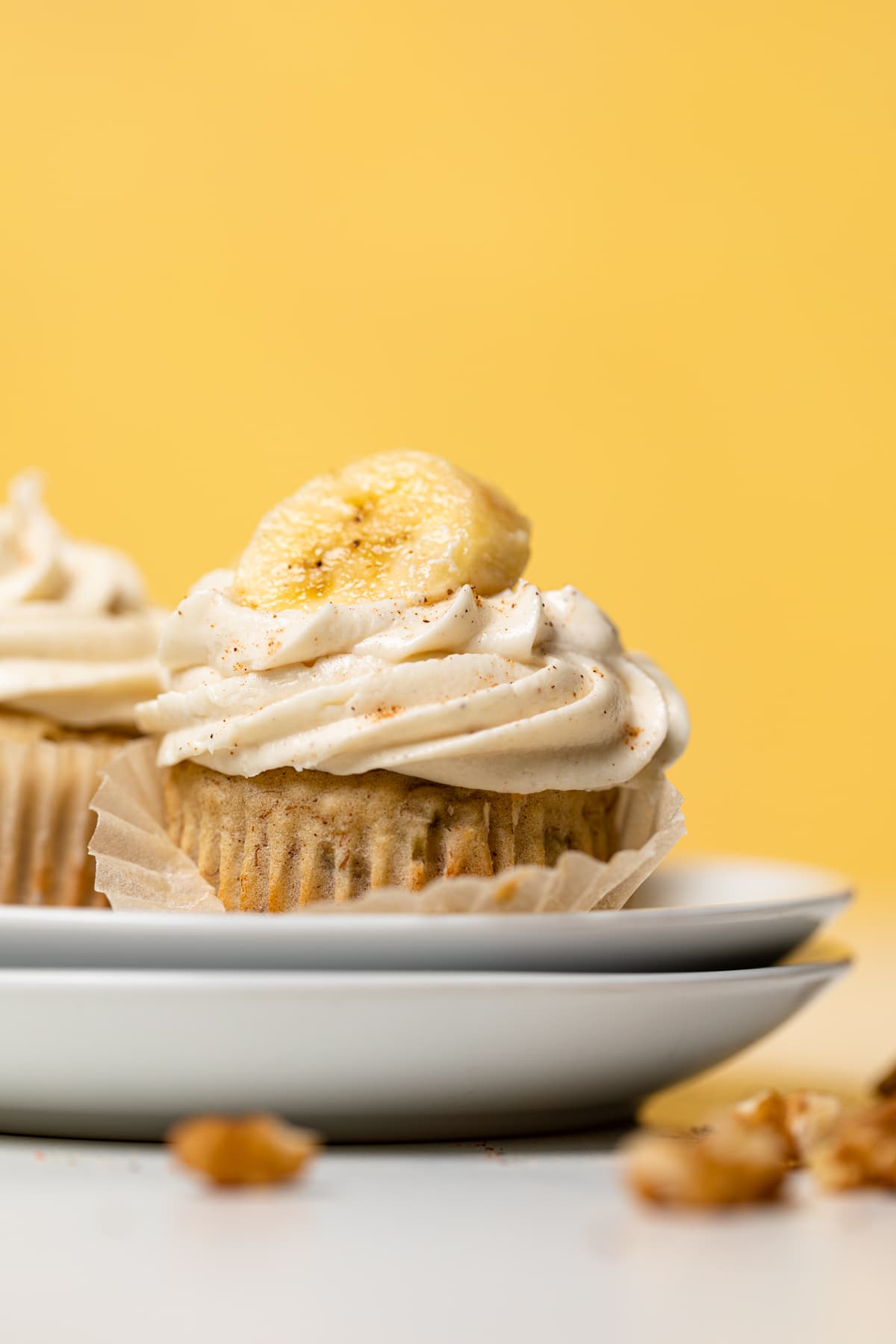 Banana Cupcakes topped with Maple Buttercream and banana slices on small plates.