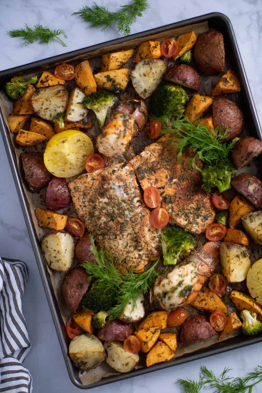 Overhead shot of a Sheet Pan of Garlic Herb Salmon, Lobster, and Veggies