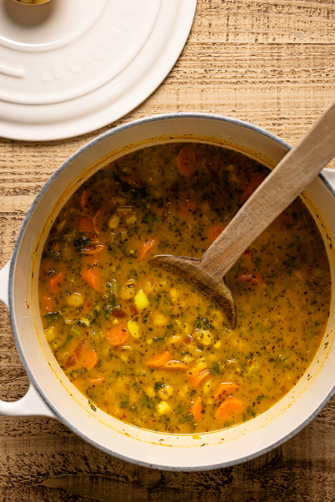 Soup in a white pot with a wooden spoon.