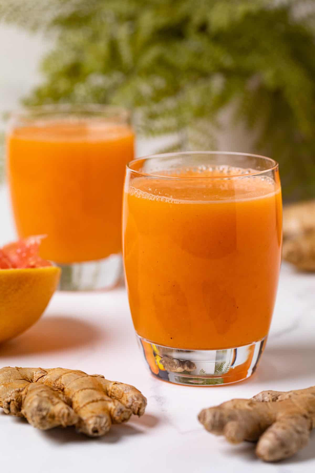 Small glasses of Carrot Ginger Citrus Turmeric Juice.