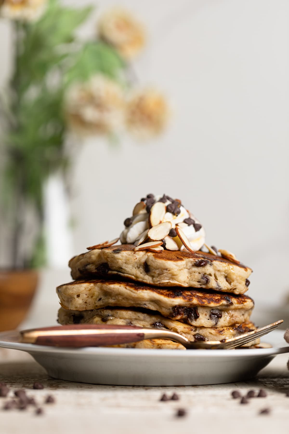 Stack of Vegan Banana Chocolate Chip Pancakes on a small plate with a fork